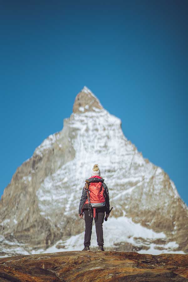 woman standing at the foot of a mountain